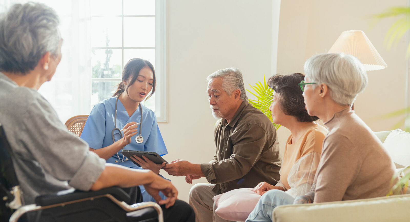 Cheerful elderly woman and men talking with female caregiver.